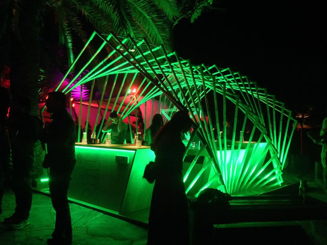 Nachtansicht der Heineken-Bar mit Besuchern, parametrische Bambusstruktur grün leuchtend mit umgebender tropischer Vegetation.