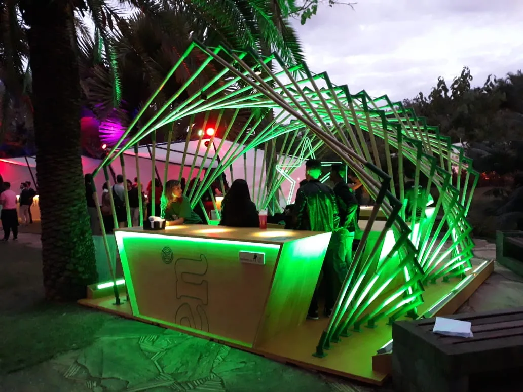 Heineken-Bar beim MECA Festival in der Dämmerung, mit der vollständigen parametrischen Bambusstruktur und grüner Beleuchtung.