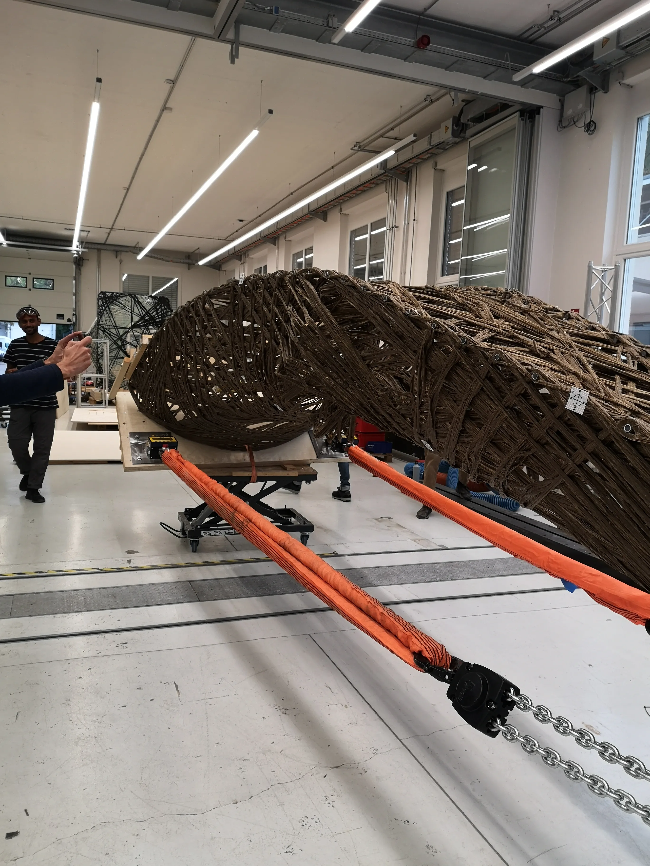 Close-up of the natural fiber wound specimen showing the complex interwoven pattern, secured with orange load straps for structural testing.