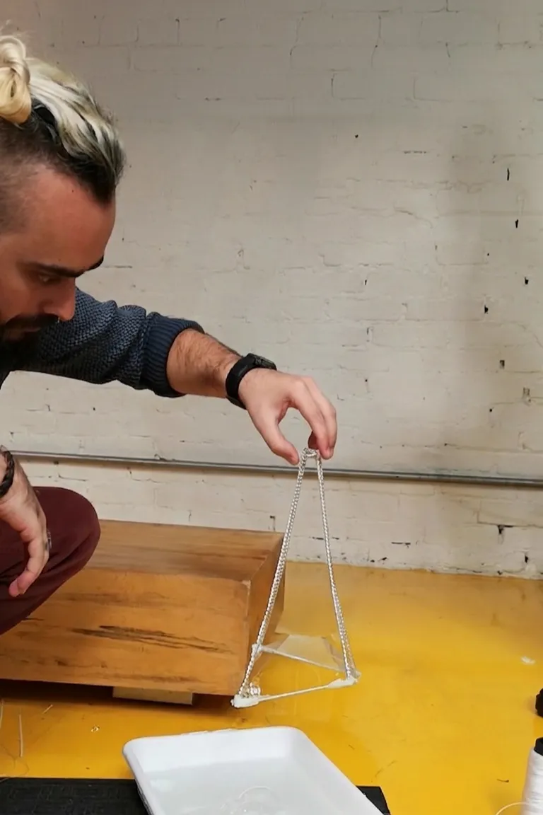 Seifenfilm, der eine pyramidale Kettenlinienfläche auf einem Drahtrahmen bildet, fotografiert von Murilo Gasparetto am Formfindungstag des Workshops.