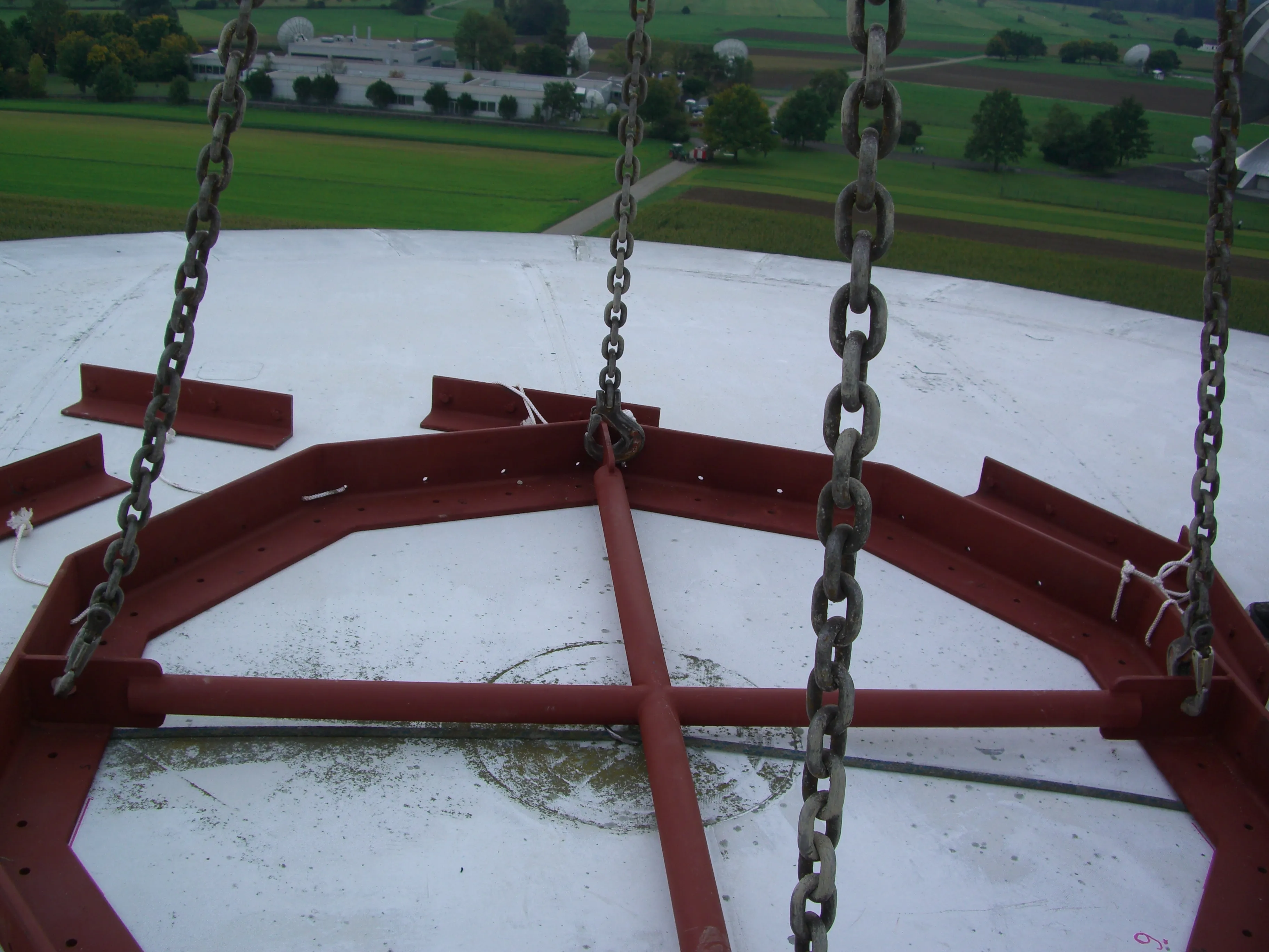 Vista do topo da estrutura da cúpula olhando para baixo, mostrando o anel de aço e as correntes usadas para levantar a membrana.