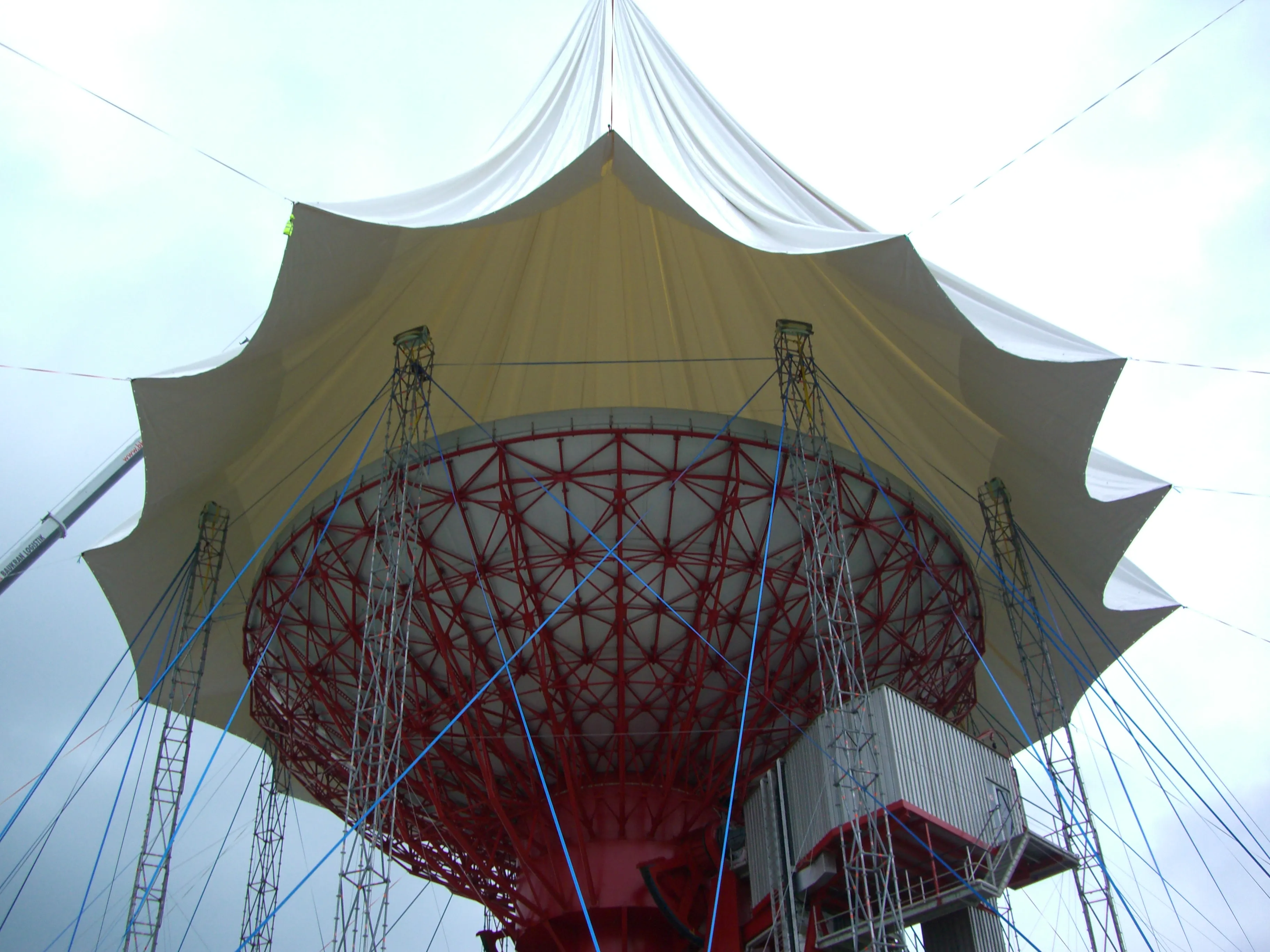 A membrana parcialmente implantada, suspensa pelo guindaste com pesos fixados para guiar o desdobramento.