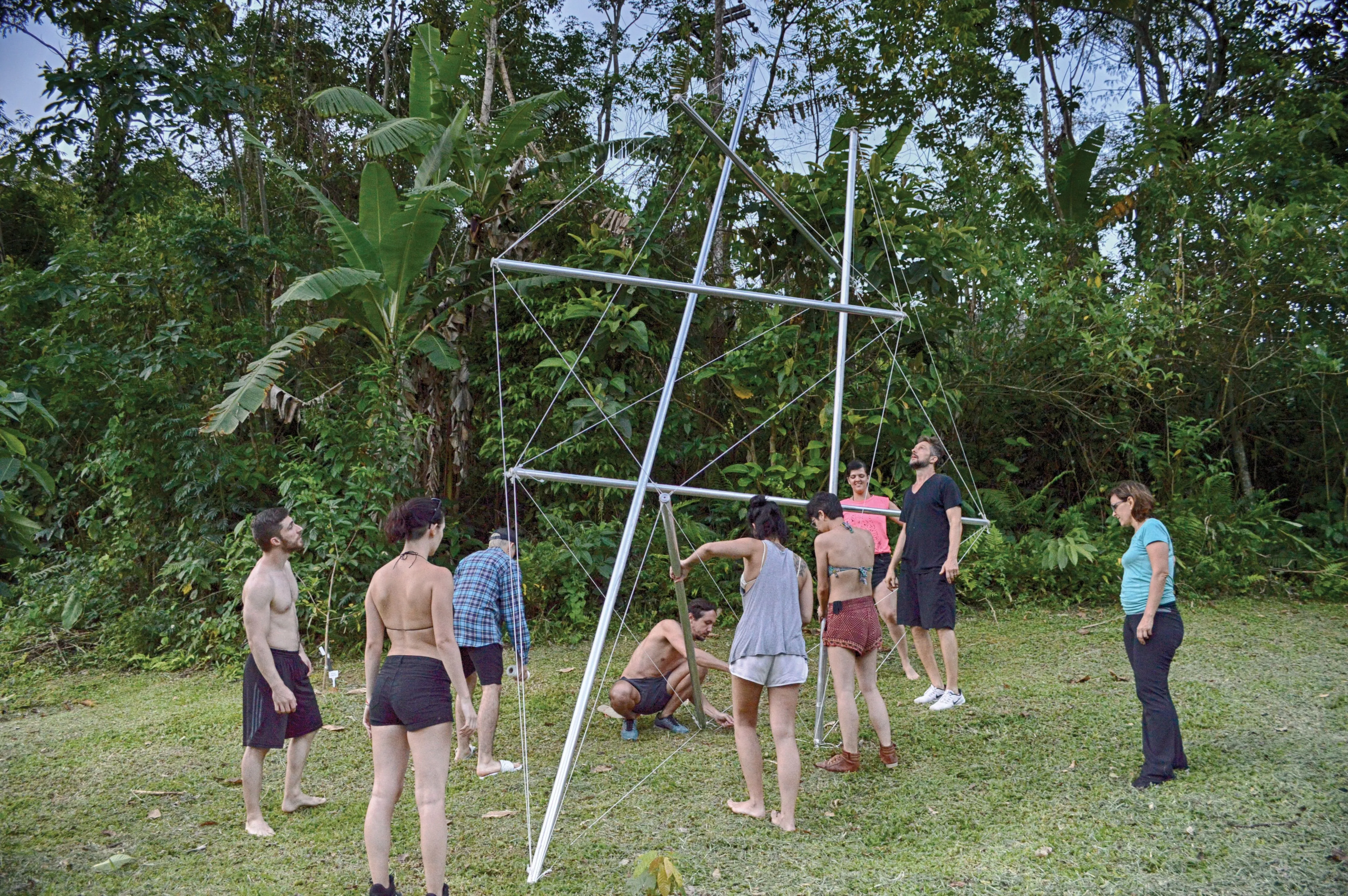Membros da equipe construindo uma estrutura de tensegridade juntos.
